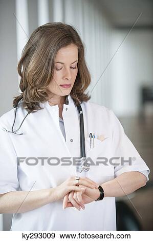 Female doctor checking the time View Large Photo Image Stock Photo - Female doctor checking the time. Fotosearch