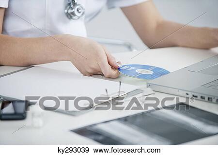 Female doctor inserting CD into a laptop View Large Photo Image Stock Photo - Female doctor inserting CD into a laptop. Fotosearch