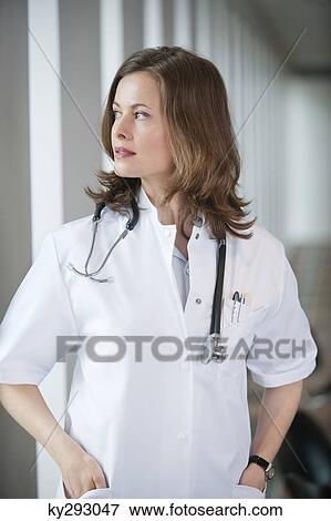 Female doctor looking out of a window View Large Photo Image Stock Photo - Female doctor looking out of a window. Fotosearch
