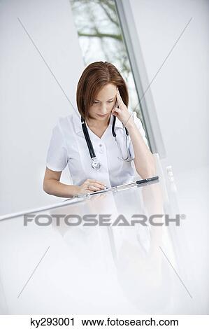 Female doctor sitting in an office looking upset View Large Photo Image Stock Image - Female doctor sitting in an office looking upset. Fotosearch
