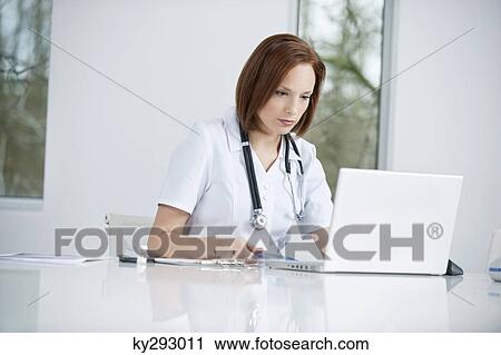 Female doctor sitting in an office inserting CD into a laptop View Large Photo Image Stock Image - Female doctor sitting in an office inserting CD into a laptop. Fotosearch