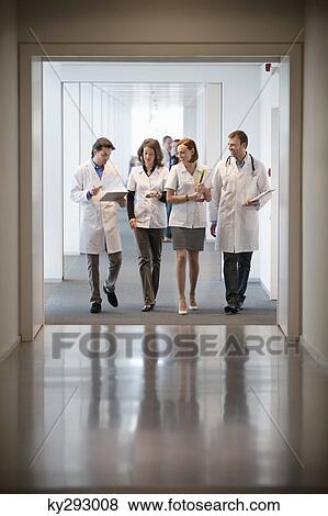 Four doctors walking at the corridor of a hospital View Large Photo Image Stock Photo - Four doctors walking at the corridor of a hospital. Fotosearch