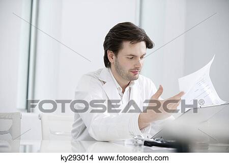 Male doctor examining a medical report View Large Photo Image Picture - Male doctor examining a medical report. Fotosearch