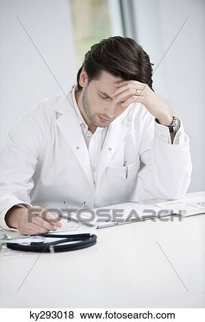 Male doctor examining a medical report and looking upset View Large Photo Image Stock Photo - Male doctor examining a medical report and looking upset. Fotosearch