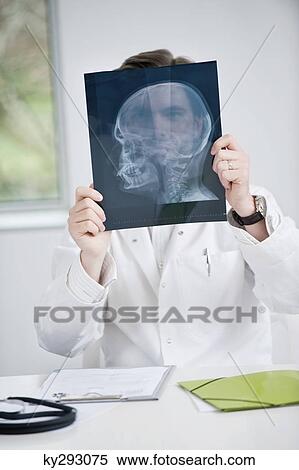 Male doctor examining an x-ray View Large Photo Image Stock Photography - Male doctor examining an x-ray. Fotosearch