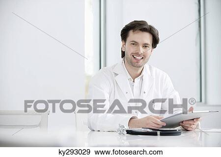 Male doctor holding a medical report and smiling View Large Photo Image Stock Photo - Male doctor holding a medical report and smiling. Fotosearch