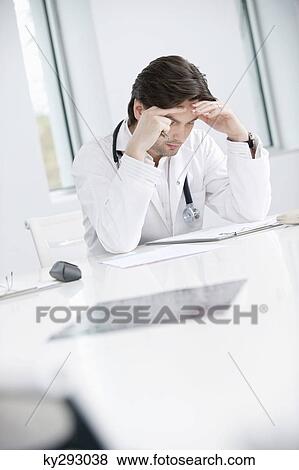 Male doctor sitting in his office and looking upset View Large Photo Image Stock Photo - Male doctor sitting in his office and looking upset. Fotosearch