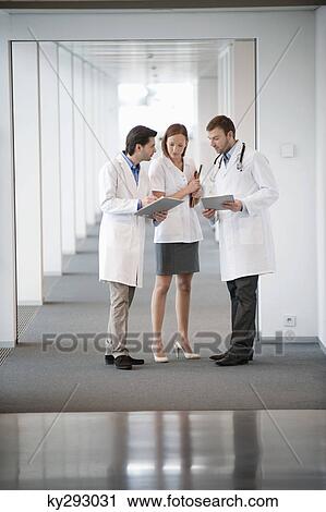Three doctors discussing a medical report View Large Photo Image Stock Image - Three doctors discussing a medical report. Fotosearch
