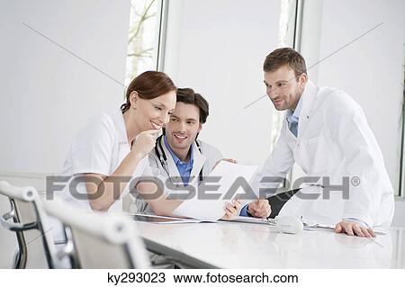 Three doctors examining a medical report View Large Photo Image Stock Image - Three doctors examining a medical report. Fotosearch