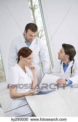 Three doctors examining a medical report View Large Photo Image Stock Image - Three doctors examining a medical report. Fotosearch