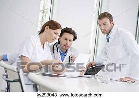 Three doctors examining a medical report View Large Photo Image Stock Image - Three doctors examining a medical report. Fotosearch