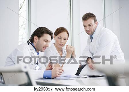 Three doctors examining a medical report View Large Photo Image Stock Photo - Three doctors examining a medical report. Fotosearch