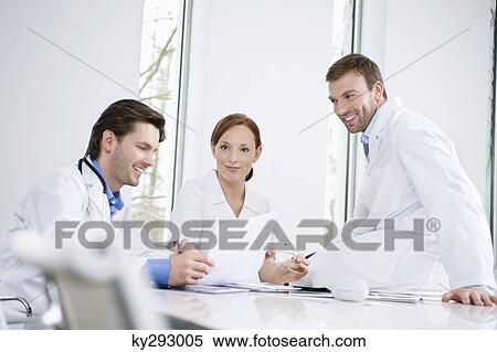 Three doctors examining a medical report View Large Photo Image Stock Photography - Three doctors examining a medical report. Fotosearch