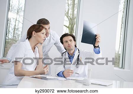 Stock Image - Three doctors examining an X-ray report. Fotosearch