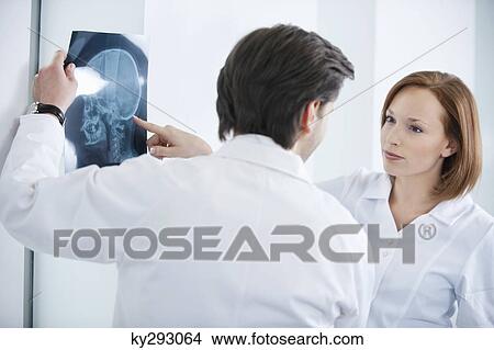 Two doctors examining an x-ray View Large Photo Image Picture - Two doctors examining an x-ray. Fotosearch