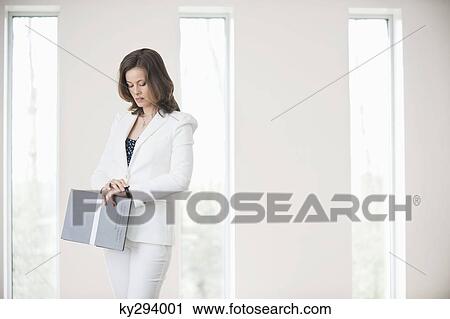 Businesswoman holding a file and checking the time View Large Photo Image Stock Image - Businesswoman holding a file and checking the time. Fotosearch