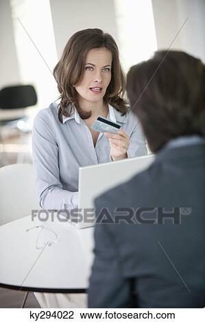 Businesswoman showing a credit card to a businessman View Large Photo Image Stock Image - Businesswoman showing a credit card to a businessman. Fotosearch