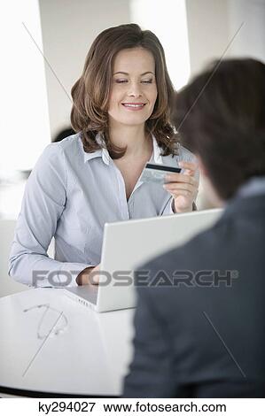 Businesswoman showing a credit card to a businessman View Large Photo Image Stock Photo - Businesswoman showing a credit card to a businessman. Fotosearch