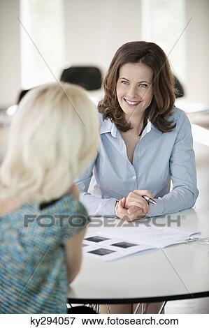 Two businesswomen discussing a report View Large Photo Image Stock Photo - Two businesswomen discussing a report. Fotosearch