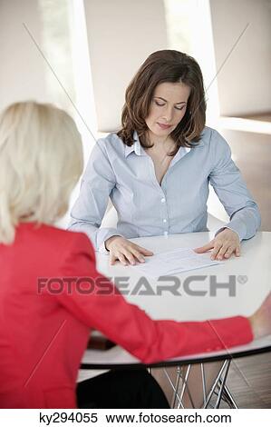 Two businesswomen discussing a report View Large Photo Image Stock Photography - Two businesswomen discussing a report. Fotosearch