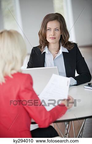 Two businesswomen discussing with each other View Large Photo Image Stock Image - Two businesswomen discussing with each other. Fotosearch
