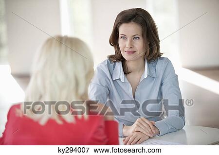 Two businesswomen discussing with each other View Large Photo Image Stock Photo - Two businesswomen discussing with each other. Fotosearch