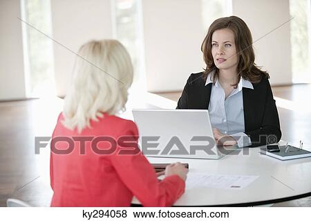 Two businesswomen discussing with each other View Large Photo Image Stock Photo - Two businesswomen discussing with each other. Fotosearch
