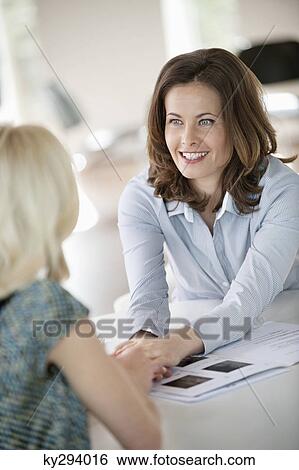 Stock Photograph - Two businesswomen talking to each other. Fotosearch