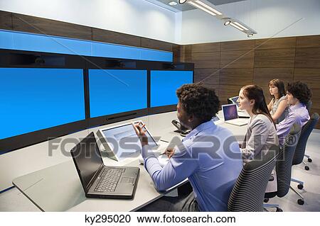 Stock Image - Business executives working in a control room. Fotosearch