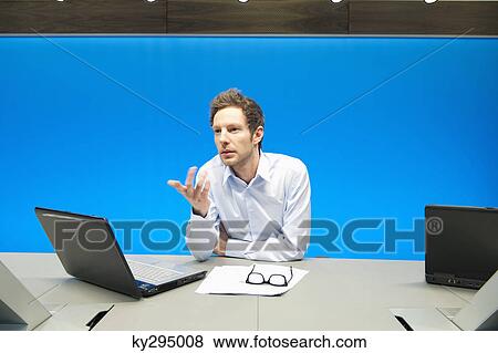 Stock Photo - Businessman working on a laptop in a conference room. Fotosearch