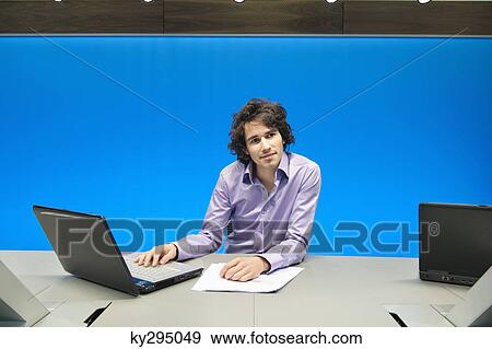 Businessman working on a laptop in a conference room View Large Photo Image Stock Photo - Businessman working on a laptop in a conference room. Fotosearch