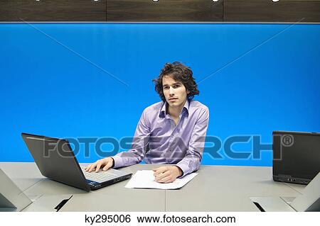 Stock Photograph - Businessman working on a laptop in a conference room. Fotosearch