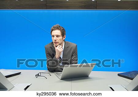 Businessman working on a laptop in a conference room View Large Photo Image Stock Photograph - Businessman working on a laptop in a conference room. Fotosearch