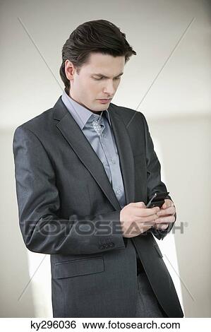 Businessman text messaging on a mobile phone View Large Photo Image Stock Photograph - Businessman text messaging on a mobile phone. Fotosearch