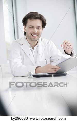 Male doctor holding a medical report and smiling View Large Photo Image Stock Image - Male doctor holding a medical report and smiling. Fotosearch