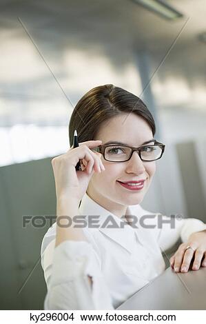 Portrait of a businesswoman adjusting her eyeglasses and smiling View Large Photo Image Picture - Portrait of a businesswoman adjusting her eyeglasses and smiling. Fotosearch