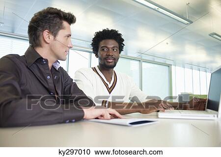 Stock Image - Business executives working on a laptop in an office. Fotosearch