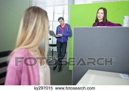 Stock Photography - Businessman using a laptop and looking at his colleagues. Fotosearch