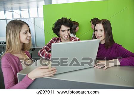 Stock Image - Businessman using a laptop with his colleagues in an office. Fotosearch