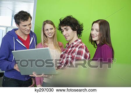 Businessman using a laptop with his colleagues in an office View Large Photo Image Stock Image - Businessman using a laptop with his colleagues in an office. Fotosearch