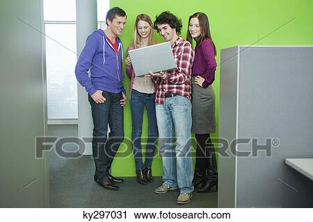 Stock Image - Businessman using a laptop with his colleagues in an office. Fotosearch