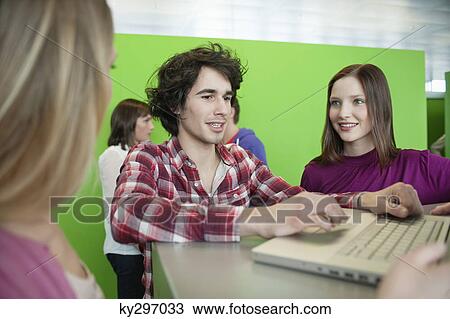 Stock Image - Businessman using a laptop with his colleagues in an office. Fotosearch