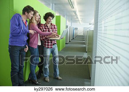 Stock Photograph - Businessman using a laptop with his colleagues in an office. Fotosearch