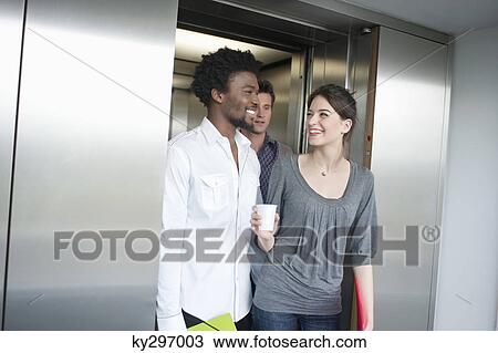 Businesswoman holding a disposable cup and talking to her colleague View Large Photo Image Stock Image - Businesswoman holding a disposable cup and talking to her colleague. Fotosearch