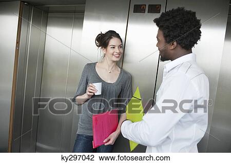 Stock Image - Businesswoman holding a disposable cup and talking to her colleague. Fotosearch