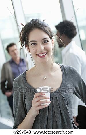 Businesswoman holding a disposable cup with colleagues in the background View Large Photo Image Stock Image - Businesswoman holding a disposable cup with colleagues in the background. Fotosearch
