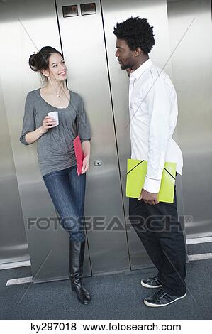 Businesswoman holding a disposable cup and talking to her colleague View Large Photo Image Stock Photo - Businesswoman holding a disposable cup and talking to her colleague. Fotosearch