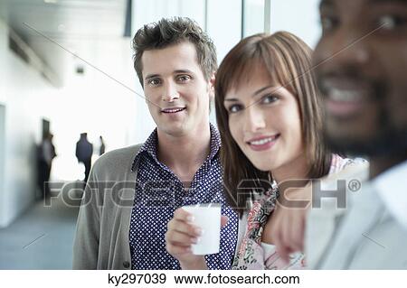 Businesswoman holding a disposable cup between her colleagues View Large Photo Image Stock Photo - Businesswoman holding a disposable cup between her colleagues. Fotosearch