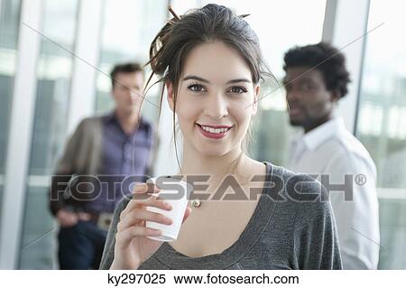 Businesswoman holding a disposable cup with colleagues in the background View Large Photo Image Stock Photography - Businesswoman holding a disposable cup with colleagues in the background. Fotosearch