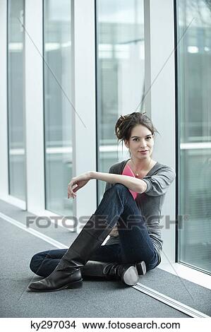 Businesswoman holding a file and sitting in an office corridor View Large Photo Image Picture - Businesswoman holding a file and sitting in an office corridor. Fotosearch